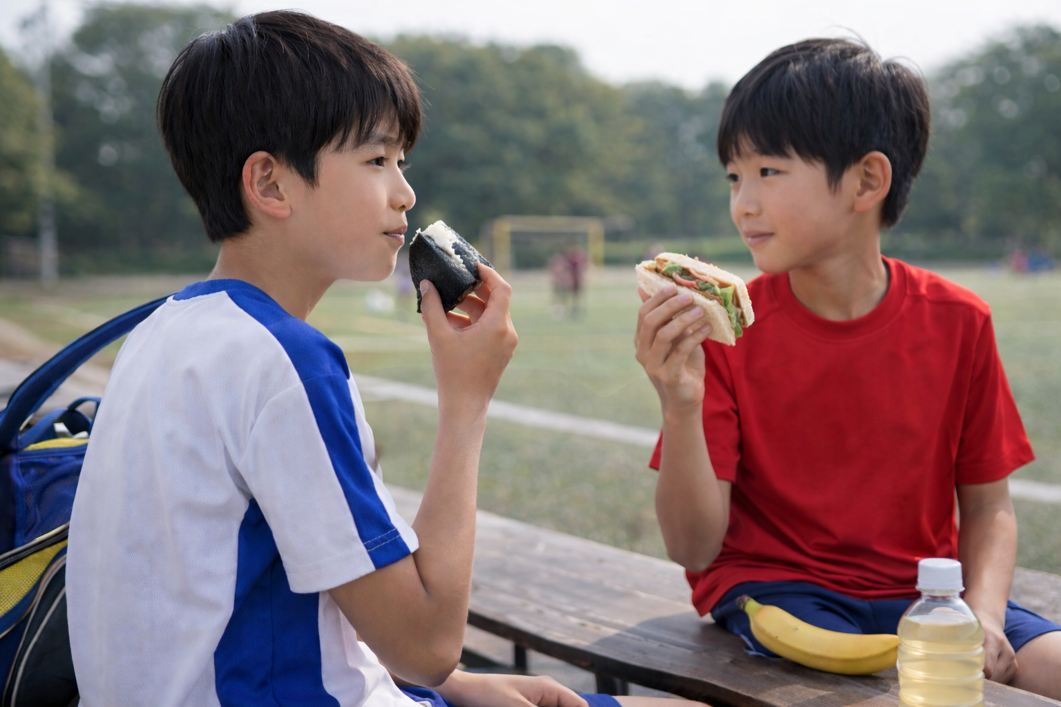 試合前にジュニアアスリートの子どもたちがおにぎりやサンドイッチで軽食をとっている様子